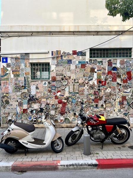 Two mopeds butting heads in front of a cacophonous art display in Tel Aviv, Israel.
