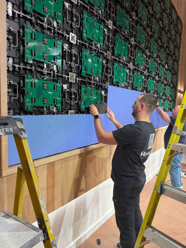 Man mounting LED screen onto wall