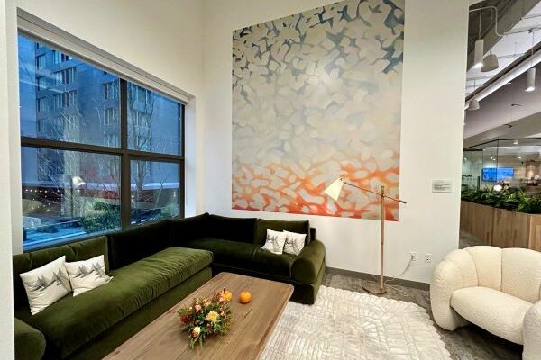 green couch and white lounge chair with large painting in background