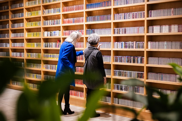 two women browsing a wall of cds
