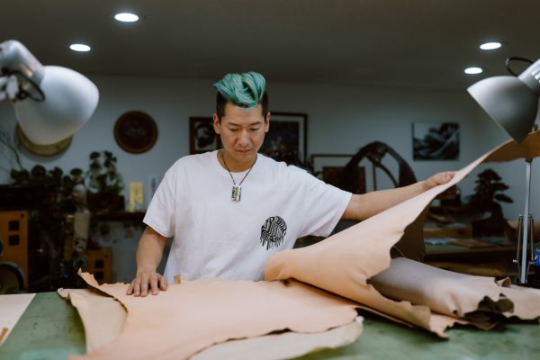 Photo of Takeshi Yonezawa with pieces of leather