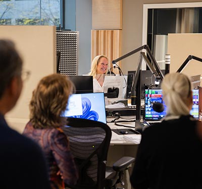 Brandi Parisi smiling in radio studio surrounded by people
