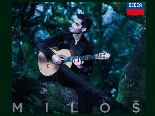 man playing the guitar with a forest in the background